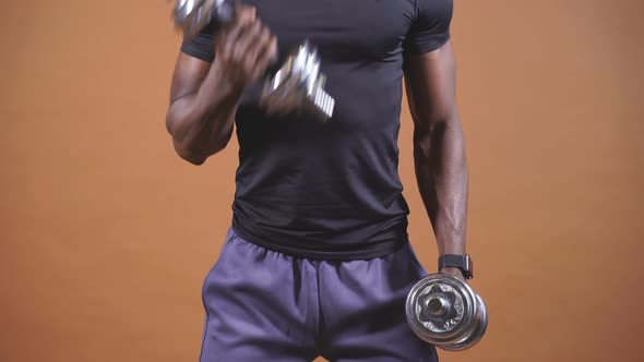 An AfricanAmerican Man Lifts Dumbbells on an Isolated Background