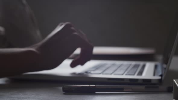 Closeup. Hands typing on laptop, fiddling with a pen. Person is bored in office. Education concept alt