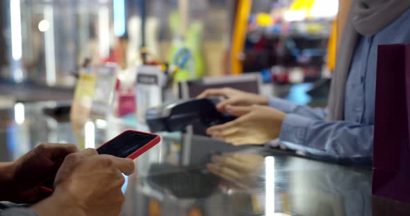 Young muslim man use smartphone paying over contactless transaction machine