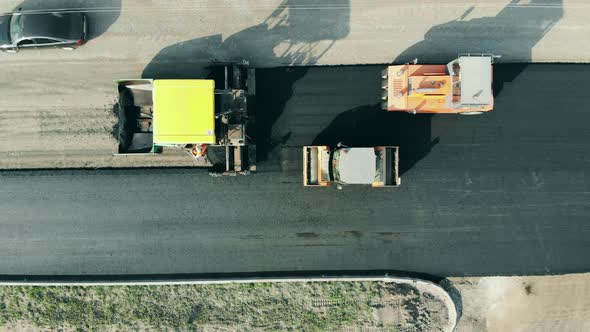 Road Construction Concept. Top View of a Roadway Getting Made By the Asphalt Spreaders alt
