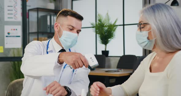 Doctor in Facemask Checking Temperature by Infrared Non-Contact Thermometer alt