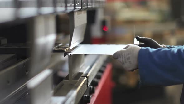 factory worker hands bending sheet metal with a press bender machine
