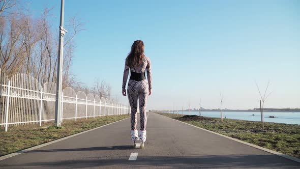 Rides Girl Roller Skating along the path on the background of a beautiful lake alt