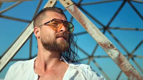 Closeup Confident Face of Bearded Fashion Male Wearing Sunglasses Posing at Grid Background alt
