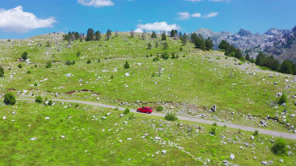 Aerial View of Road with Red Car in Beautiful Mountains in Komovi Montenegro alt