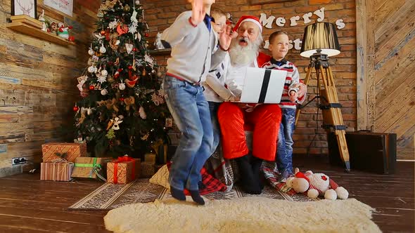 Santa Claus Plays with Three Kids on Computer.