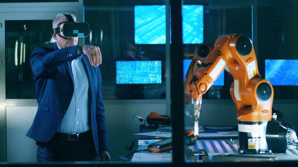 A Man in a Business Suit Is Wearing VRglasses and Managing a Robot alt