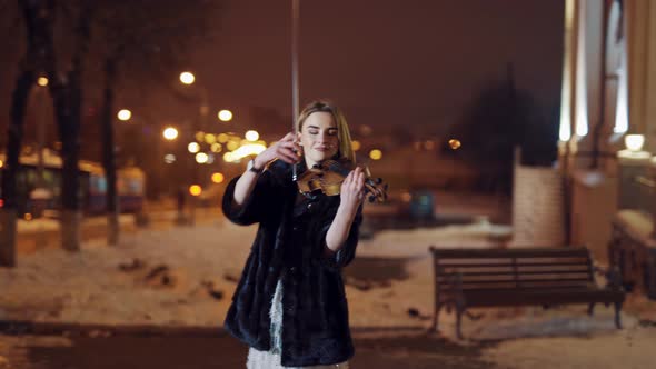 A Beautiful Girl is Playing the Violin in the Centre of the City in the Winter alt