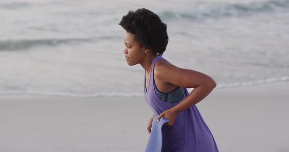 African american woman with yoga mat on sunny beach alt