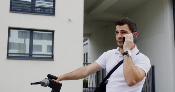 Businessman Listening to Mobile Phone While Standing with Electric Scooter alt