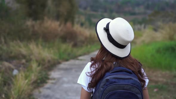 slow-motion of woman with backpack walking on footpath in nature