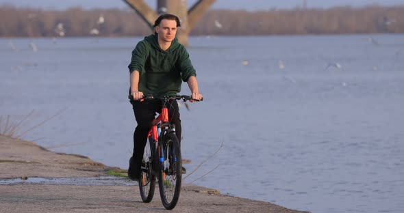 Bicyclist Riding Bike at River Embankment Slow Motion alt
