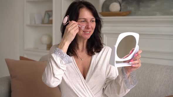 Beautiful Lovely Woman in Dressing Gown Makes Face Massage with Gua Sha Tool alt