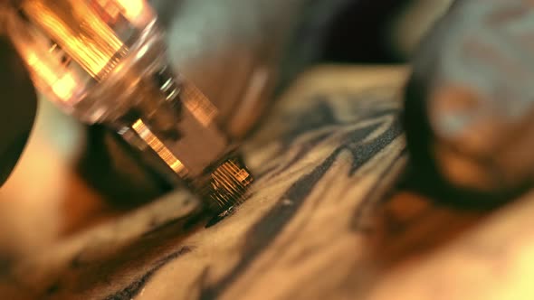 Up Close Shot of Tattooist Machine with Mag Needle Drawing Black Outline on Skin