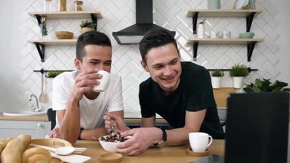 Young Gay Couple is Sitting at the Kitchen Table Eating Breakfast alt