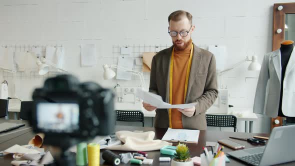 Creative Tailor Recording Video for Internet Vlog Showing Sketches and Speaking alt