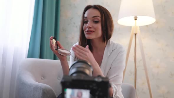 Beauty vlogging. Blogger recording makeup tutorial on camera alt