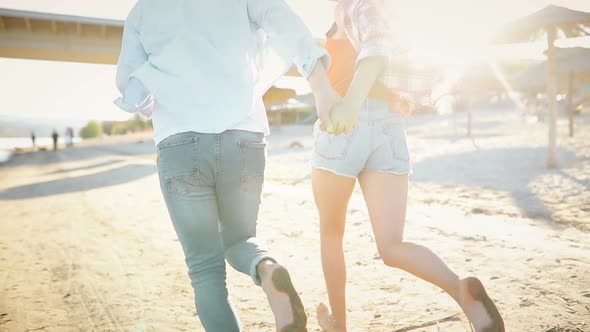Carefree Couple in Love Running Barefoot on Beach