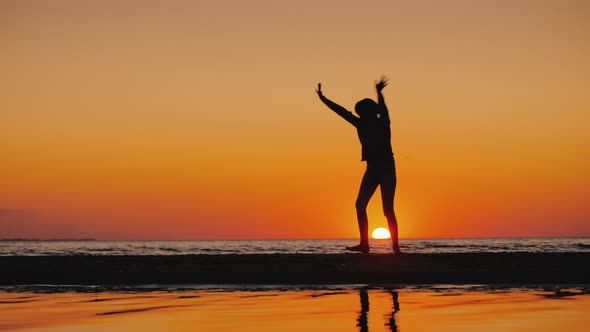Silhouette of a Little Girl Making Acrobatic Wheel in in a Picturesque Place By the Sea alt