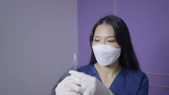Asian Doctor Holds Needle for Aesthetic Procedure and Looks at the Camera alt