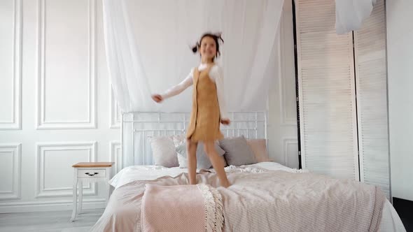 Funny Adorable Happy Kid Brunette Girl Jump on Bed Cute Little Child Having Fun Dancing to Music
