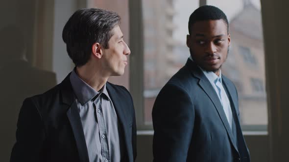Two Coworker Colleagues Stand in Modern Company Office Look Out Window Happy Caucasian Business Man alt