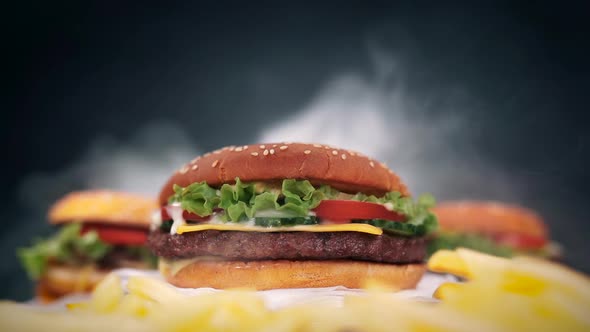 Fresh yummy grilled burgers rotating on black smoke background. Fast food concept
