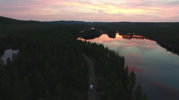 Car Driving On Road in Forest at Sunset