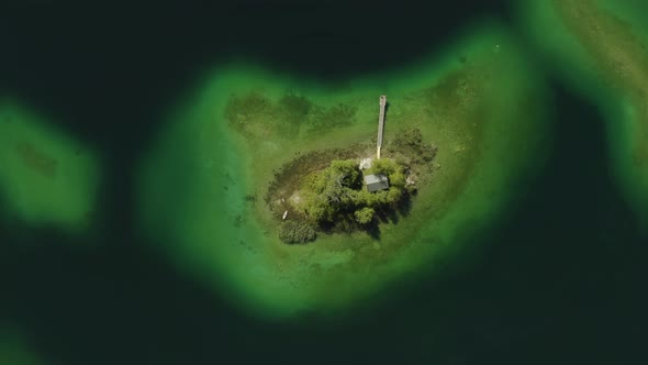 Isolated island Maximiliansinsel in German lake Eibsee, aerial drone view alt