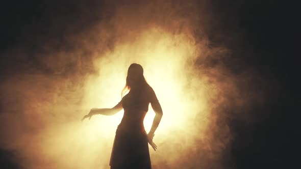 Woman Dancing in Smoke on a Dark Background