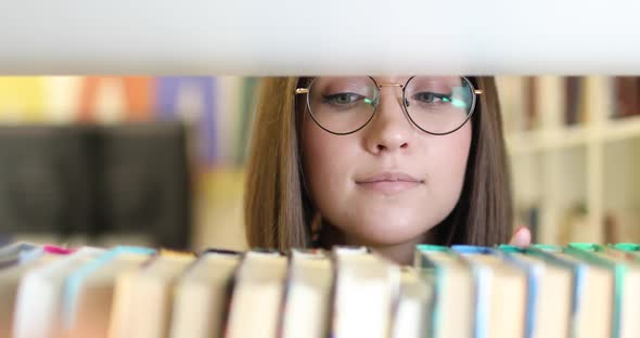 Young Beautiful European Female Student Wearing Glasses Choosing Book