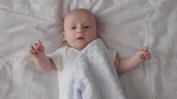 Newborn Baby Boy Lying on Bed and Covered with Blanket