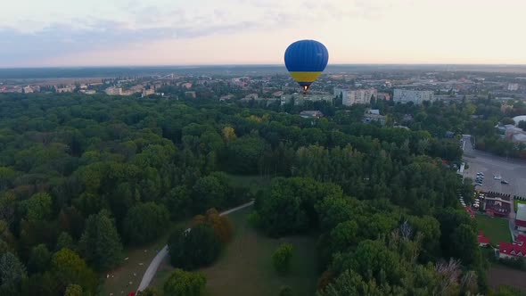 Hot Air Balloon Floating Over City Park in Early Morning, Rising up Into Sky alt