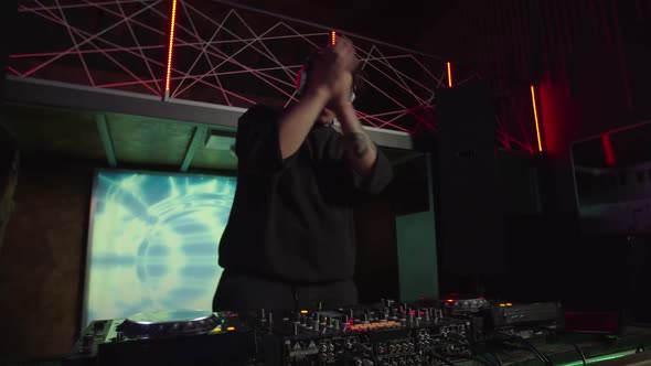 Professional Black Dj in Headphones Mixing Track on Soundboard and Turntable Console at Nightclub alt