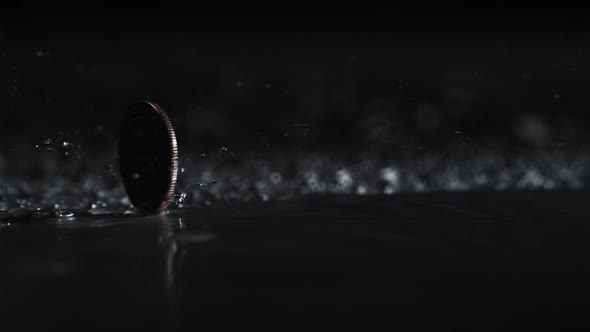 US currency, quarter (25 cents) coin spinning on water surface. Slow Motion. alt