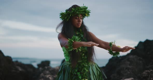 Woman performing traditional Hawaiian hula by the ocean alt