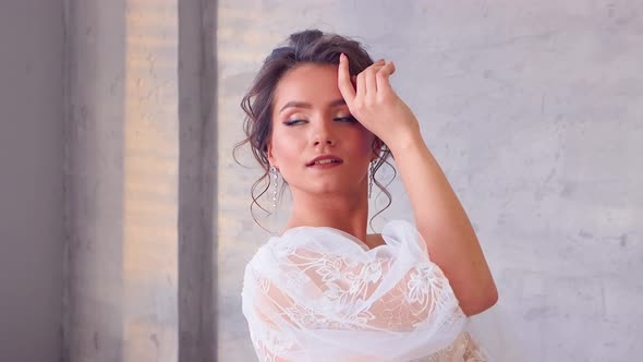 The Girl in a White Dress Poses for the Photographer Turning Beautifully alt