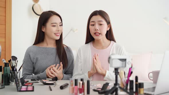 Two young Asian woman beauty vloggers doing cosmetic review live streaming at home