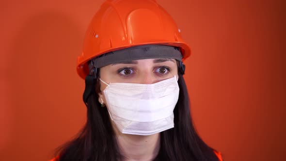 Portrait of Young Woman in Medical Mask on Her Face on Orange Background alt