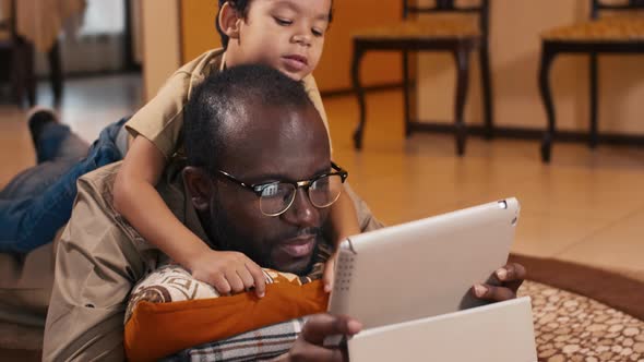 African American man and his son watching cartoon on tablet computer