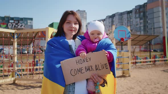 Portrait of a Joyful Ukrainian Woman Holding a Child and a Ukrainian Flag alt