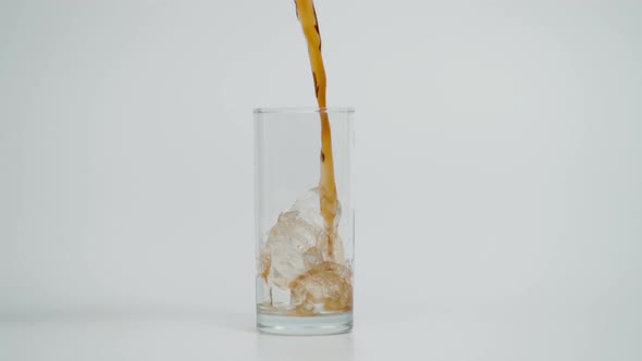 Slow Motion of Pouring Cola in Glass with Ice White Background alt