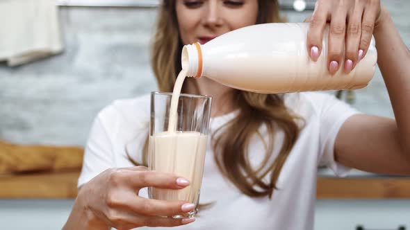 Close Up Hands of Adorable Girl Poured Liquid Dairy Beverage at Glassware alt