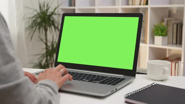 Business woman working on a laptop with a green screen. Cropped frame.