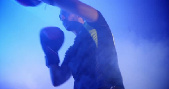 Young man training in a dark room for a box match