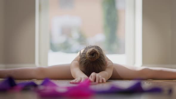 Motivated Confident Teen Gymnast Looking at Camera Stretching Muscles Sitting on Twine alt