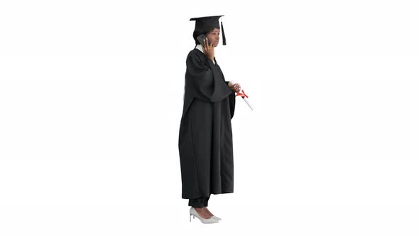 African American Female Student in Graduation Robe Talking on the Phone on White Background