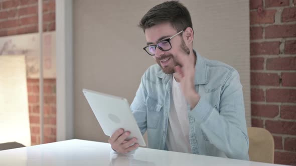 Cheerful Young Male Designer Doing Video Chat on Tablet  alt