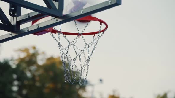 Basketball ball hits into hoop outdoors. Successful throw. Basketball player scores a goal alt