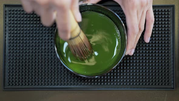 4K Asian woman barista making iced matcha green tea latte serving to customer at cafe alt